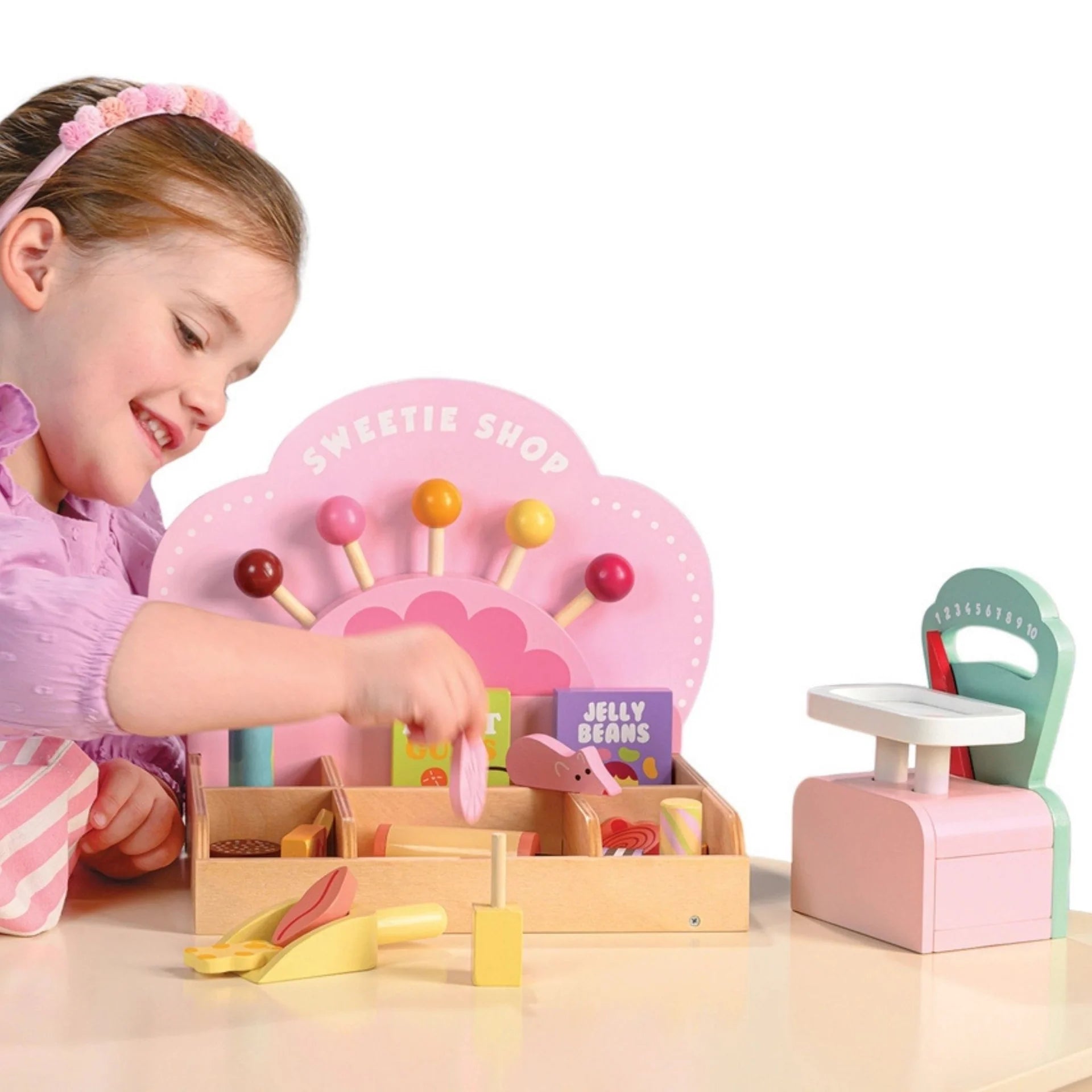Child playing with a toy sweet shop set on a white background