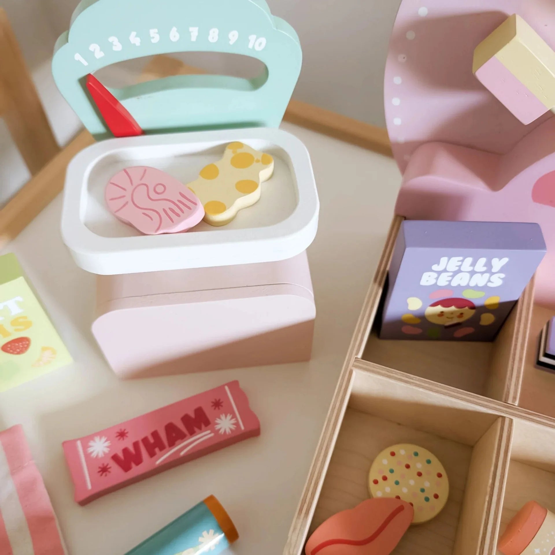 Toy candy container with various toy candies on a wooden surface