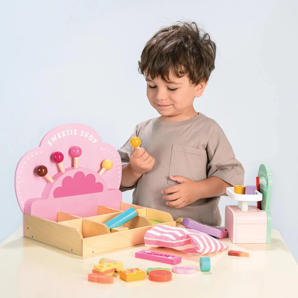 Child playing with a wooden toy set on a light surface with a light blue background